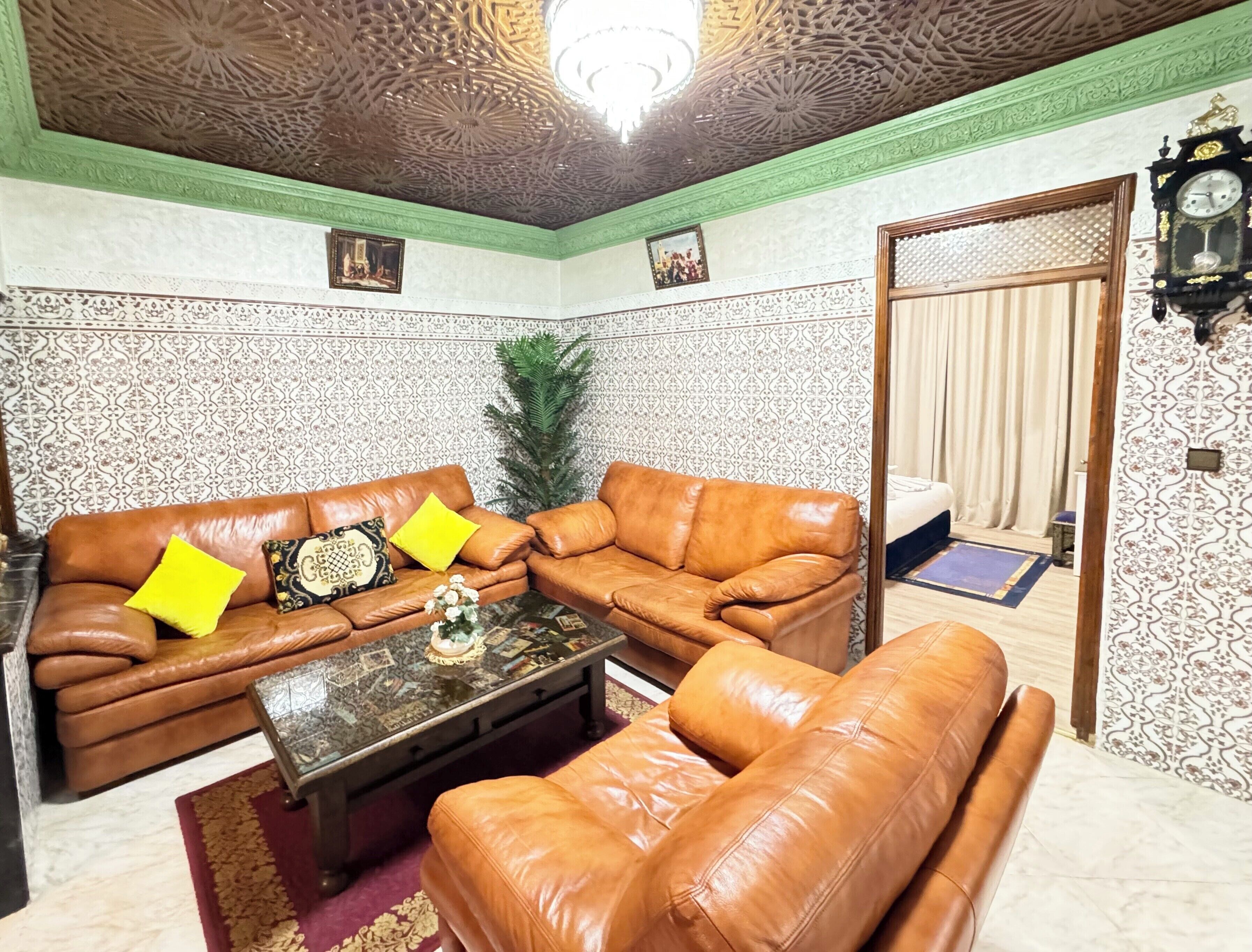 A living room with a brown leather sofa set, a coffee table, and patterned wallpaper.