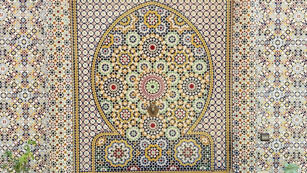 Pared de azulejos con patrones geométricos intrincados y un arco central.