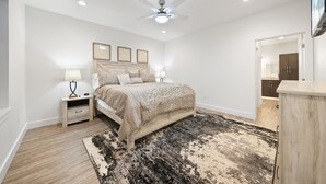 A bedroom with a bed, nightstands, a ceiling fan, and a large rug. - Brand new, 3 Bedroom Suite in Fort Morgan! (Fort Morgan)