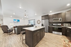 A modern kitchen with dark cabinets, stainless steel appliances, and a central island.