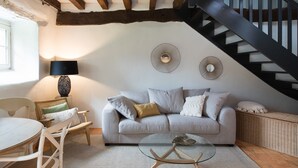 A cozy living room with a sofa, a coffee table, a lamp, and a staircase. - VAU D'ARZ MANOR - Gîte LA GACILLY (MALANSAC)