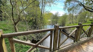 A wooden deck with a railing overlooking a river, surrounded by trees and greenery. - VAU D'ARZ MANOR - Gîte Rochefort (MALANSAC)