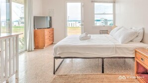 A bedroom with a bed, a TV, and a view of the sea. - 435 East Lake (Montauk)