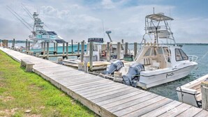 A dock with two boats, one larger and one smaller, connected by a wooden walkway. - 435 East Lake (Montauk)