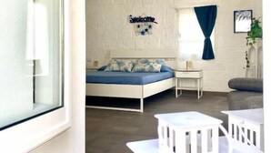 A modern room with a bed, a small table, a chair, and a window with curtains.