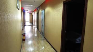 A hallway with doors on both sides, a fire extinguisher on the left, and a dark room on the right.