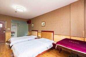 Ein Hotelzimmer mit zwei Betten, Holzboden, einem Spiegel und einer Tür.