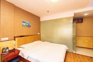 Ein Hotelzimmer mit Bett, Nachttisch, Spiegel und einem kleinen Gemälde an der Wand.