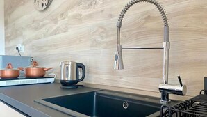 A modern kitchen with a black sink, stainless steel faucet, and copper pots on the counter. - Allegria Pool House (Monopoli)