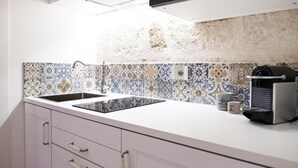 Et køkken med en hvid bordplade, en sort vask og et flisebeklædt backsplash.