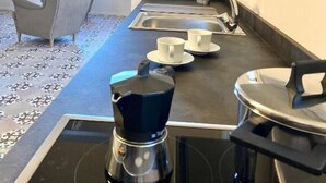 A modern kitchen with a coffee maker, two cups, and a sink.
