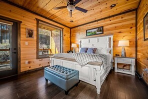 Ein Schlafzimmer mit Holzbalkendecke, einem Bett mit weißem Kopfteil, einer blauen Bank und zwei Nachttischen mit Lampen.