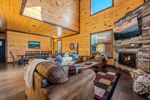Ein geräumiges Wohnzimmer mit Kamin, Holzwänden und einem großen Fenster.