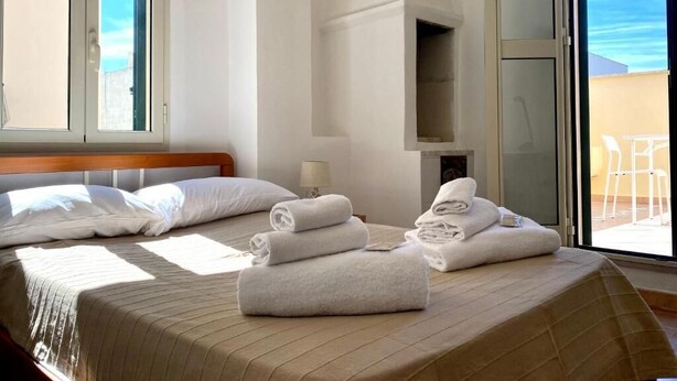 A hotel room with a bed, two windows, a lamp, and a view of the outside. - La Terrazzina (Monopoli)
