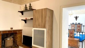 A room with a fireplace, wooden cabinet, and a bed with a blue bedspread. - La Terrazzina (Monopoli)