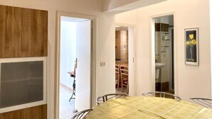A dining area with a table and chairs, a wooden accent wall, and a door leading to another room. - La Terrazzina (Monopoli)
