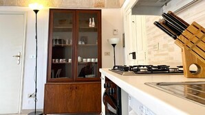 Een keuken met een houten kast, een gasfornuis en een messenblok.