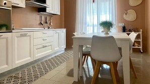 A modern kitchen with white cabinetry, a stainless steel range hood, and a dining area with a white table and chairs. - Bella Luna Apulian Living (Monopoli)