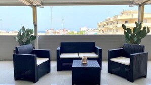 A covered outdoor seating area with wicker furniture and potted plants. - Bella Luna Apulian Living (Monopoli)