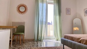 A room with a bed, a chair, a desk, a radiator, and a window with curtains. - La Vue Est Belle (Monopoli)