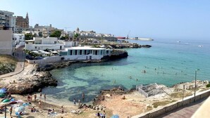 A coastal town with a beach, clear waters, and buildings along the shore. - La Vue Est Belle (Monopoli)