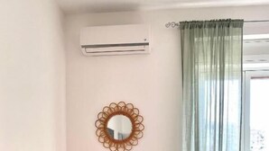 A room with a radiator, a wooden table, a green chair, a decorative mirror, and a green curtain. - La Vue Est Belle (Monopoli)