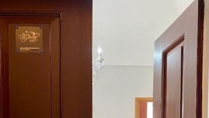 Une porte en bois avec une plaque, un canapé rouge avec un coussin et un sol carrelé.