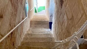 A stone staircase with a metal handrail, leading to a bright room with a view of greenery outside. - Pearl of the Sea (Monopoli)