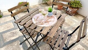 A wooden table with two chairs, a small potted plant, and two glasses of white wine on a tiled patio. - Pearl of the Sea (Monopoli)