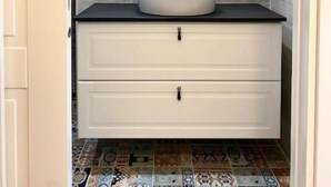 A bathroom with a round mirror, white sink, and a tiled floor. - Porto Bianco (Monopoli)