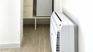 A compact room with a white radiator, a small white cabinet, and a black device on top. - Porto Bianco (Monopoli)