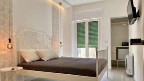 A bedroom with a bed, bedside table, and a wall-mounted TV. - Porto Bianco (Monopoli)