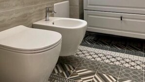 A modern bathroom with a toilet, bidet, and sink. - Red Port (Monopoli)