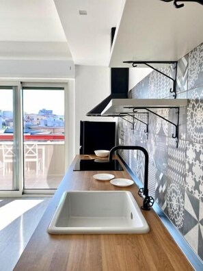 Una cocina moderna con un amplio ventanal, un grifo negro y un lavamanos blanco.