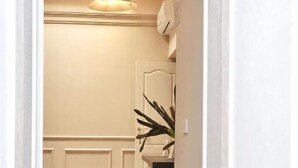 A hallway with a herringbone floor, a pendant light, a plant, and a door leading to another room. - MARIACHIARA (Monopoli)