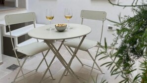 A white outdoor seating area with two chairs and a table, two wall-mounted lights, and a window. - MARIACHIARA (Monopoli)