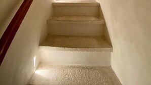 A staircase with a wooden handrail leading to a landing with a small window. - Matthias (Monopoli)