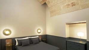 A modern bedroom with a large bed, two bedside tables, a dresser, and a skylight. - Matthias (Monopoli)