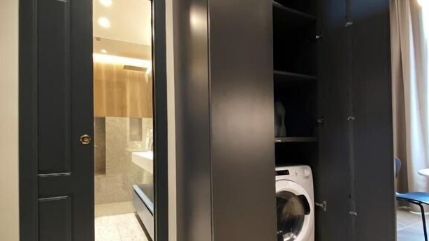 A modern interior with a black wardrobe, a washing machine, and a tiled floor. - Matthias (Monopoli)