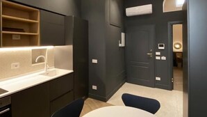 A modern kitchen with a white countertop, dark cabinetry, and a round dining table. - Matthias (Monopoli)