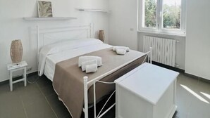 Moderni makuuhuone, jossa on sänky, yöpöydät, ikkuna ja patteri.
