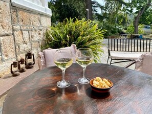 A round wooden table with two glasses of white wine and a bowl of snacks. - Dalia home (Monopoli)