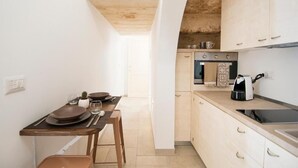 Cocina compacta con comedor, que incluye una mesa de madera, sillas y un horno empotrado.