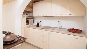 Una cocina con armarios de madera clara, un lavabo y una cafetera.