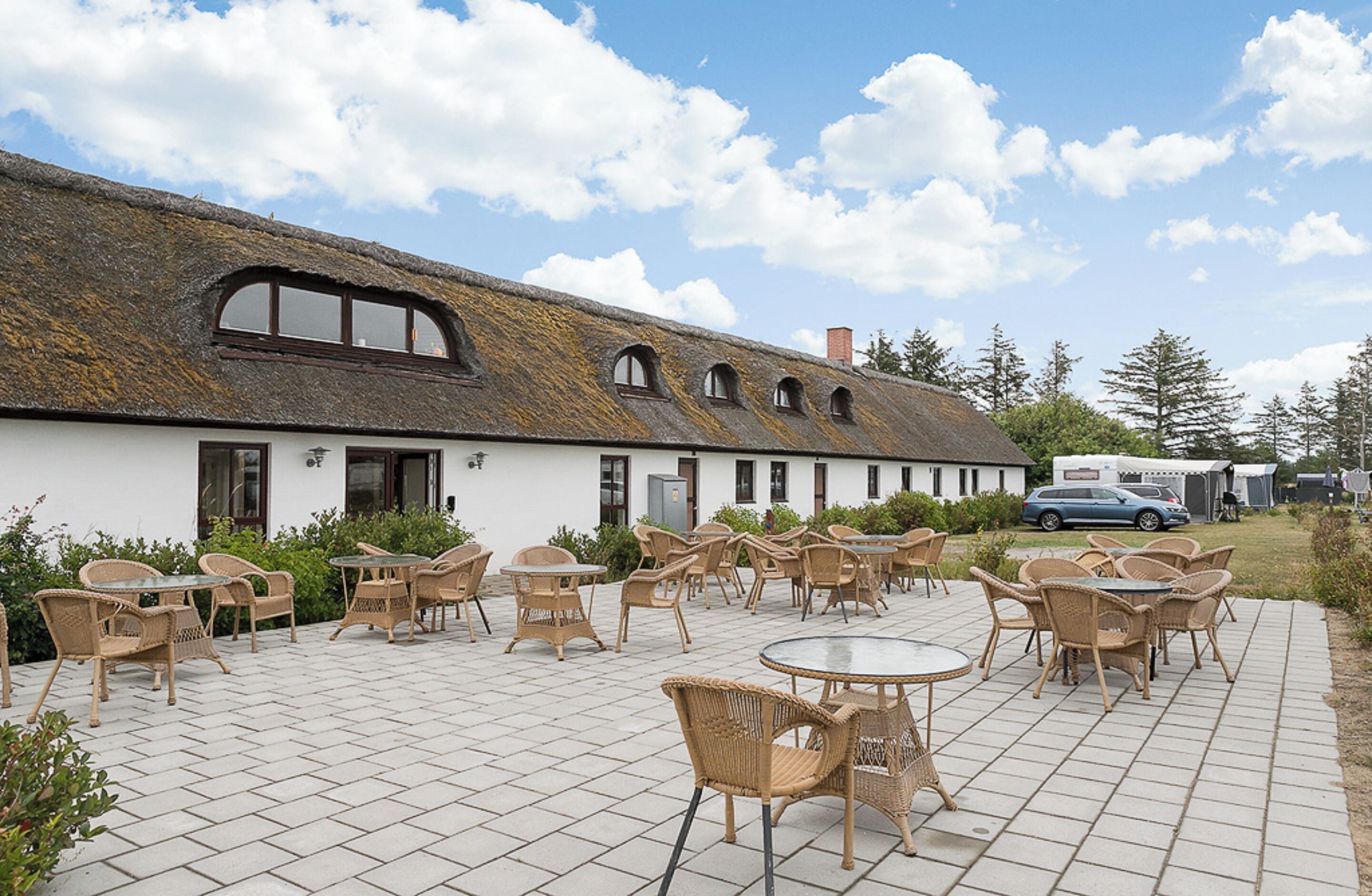 A building with a thatched roof and a patio area with wicker furniture.