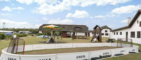 A playground area with a soccer goal, swings, and a picnic table.