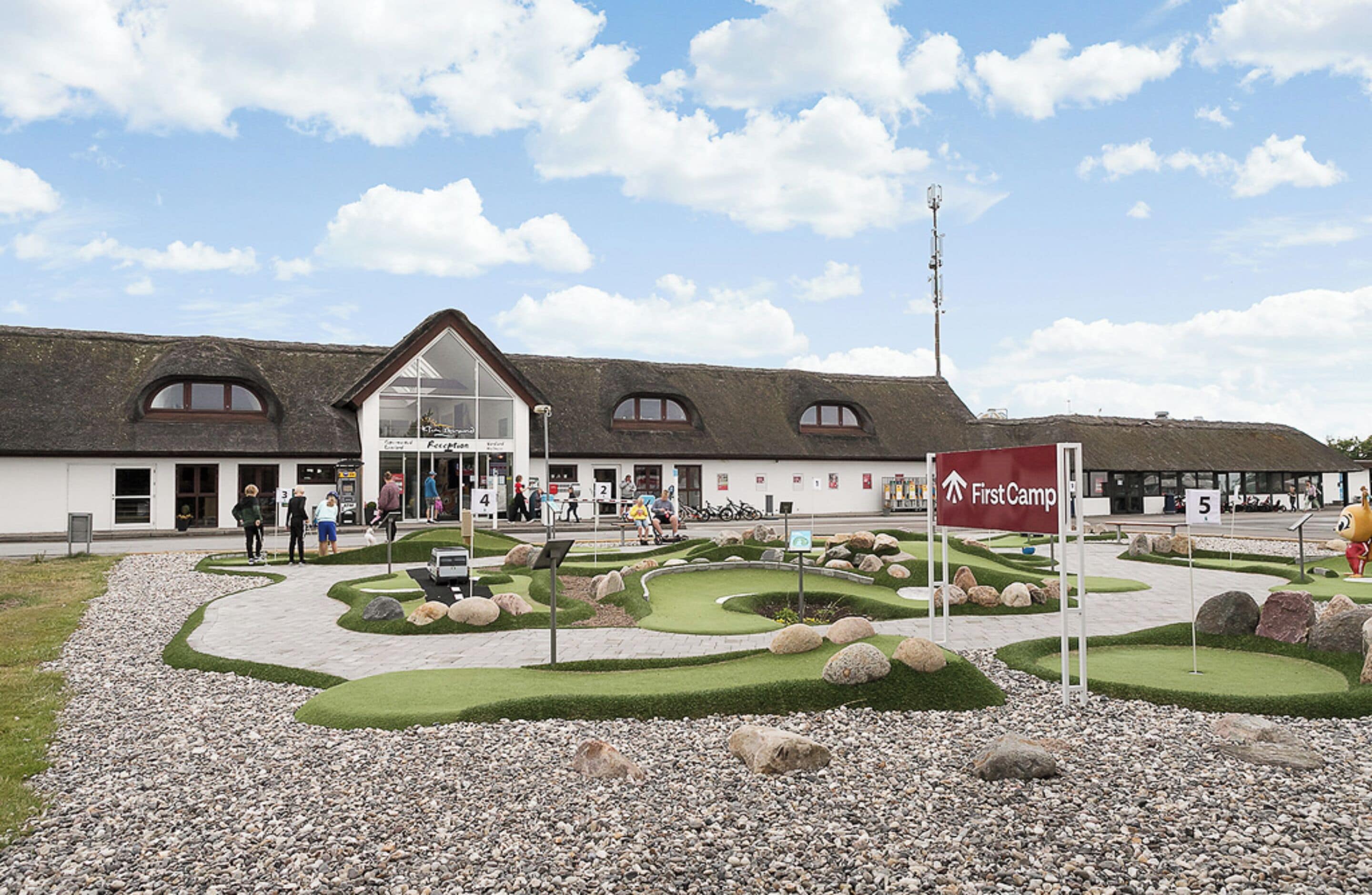 A building with a modern design, featuring a large glass entrance and a sign for 'First Camp'.