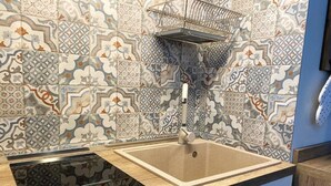 A kitchen with patterned tiles, a sink, a countertop, and a cabinet. - Vitti Suite 5 (Monopoli)