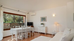 Ein Zimmer mit Esstisch, Stühlen, einer Couch, einer Lampe, einem Fernseher und einer Steinwand.