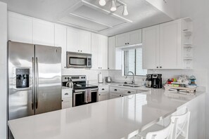 Enjoy cooking in this well-lit kitchen with a refrigerator, microwave, and large island with seating.